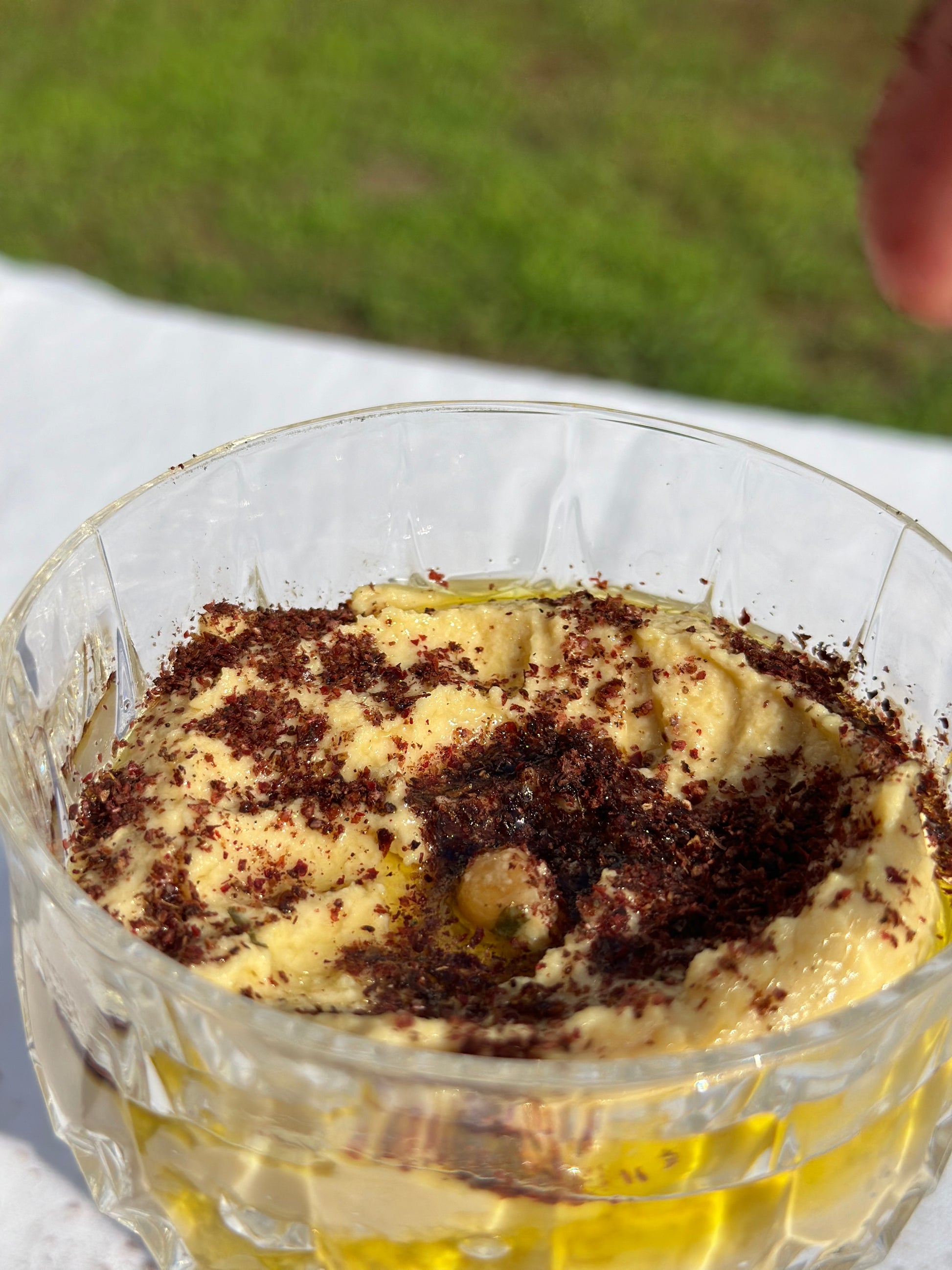 Ein elegantes Glas mit cremigem Hummus, verfeinert mit einem großzügigen Streuen von Honeydew libanesischem Sumach