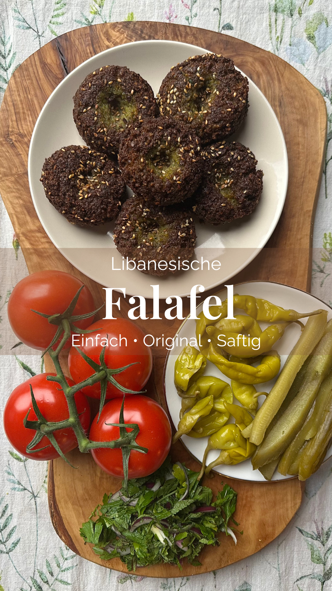 Frisch frittierte libanesische Falafel mit Sesam, Tomaten, Pickles und Kräutern auf Holzbrett angerichtet.