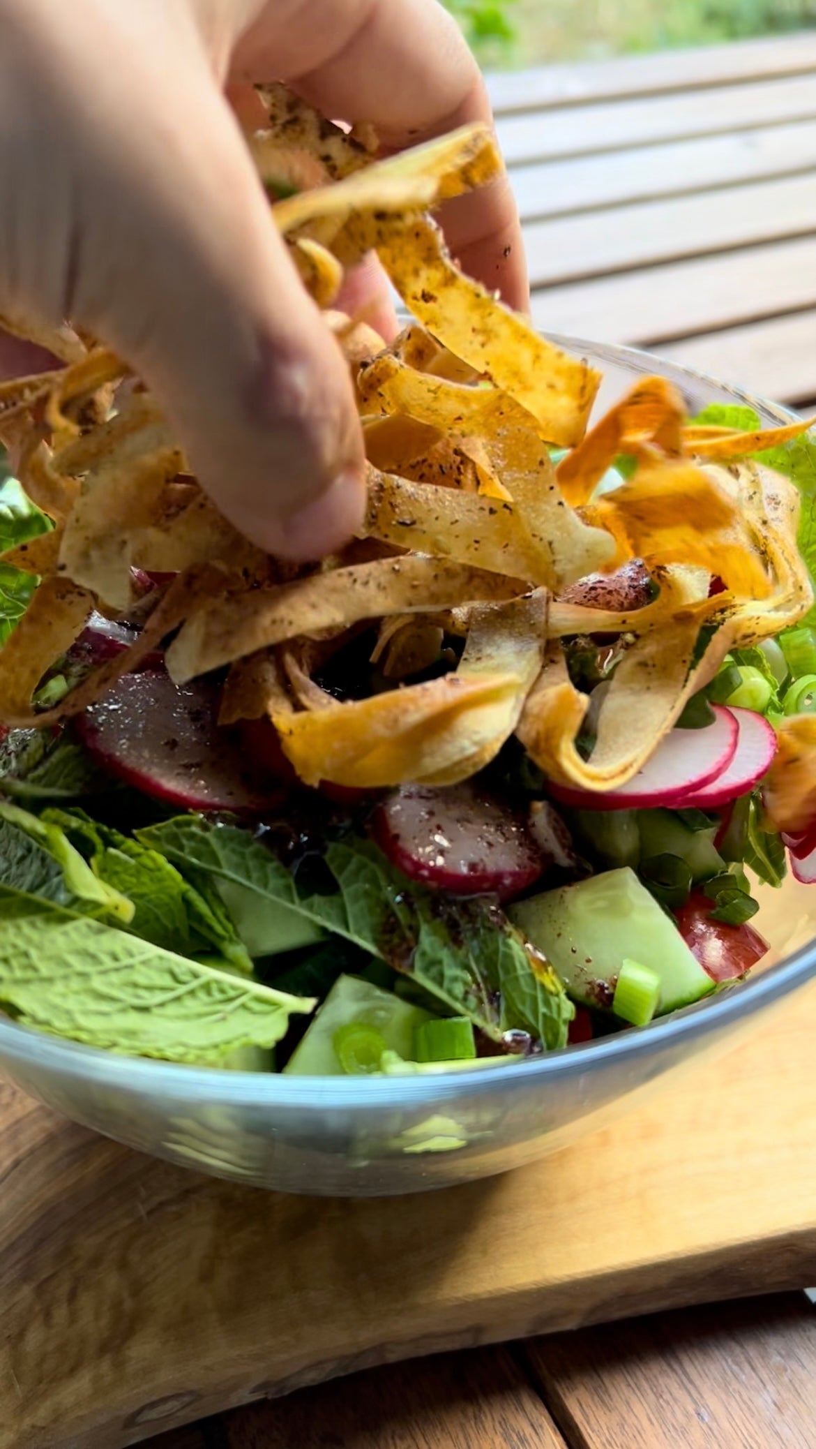 Libanesischer Fattoush-Salat in einer Glasschüssel, mit frischen Gurken, Radieschen, Minze und knusprigen Za'atar-Brotchips als Topping